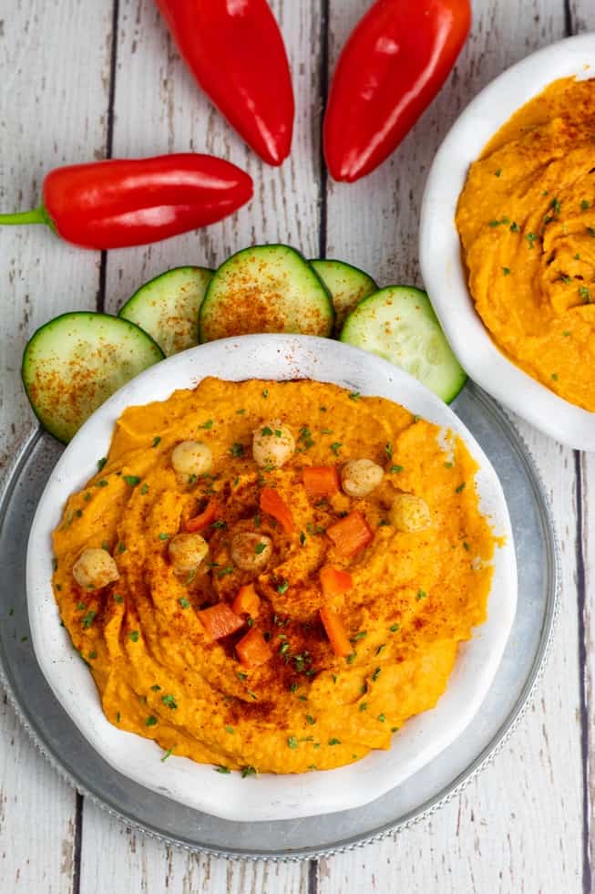 overhead photo of roasted red pepper hummus in white bowls