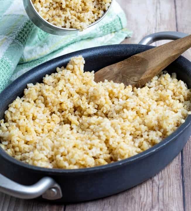 cooked bulgur in pan on wooden table