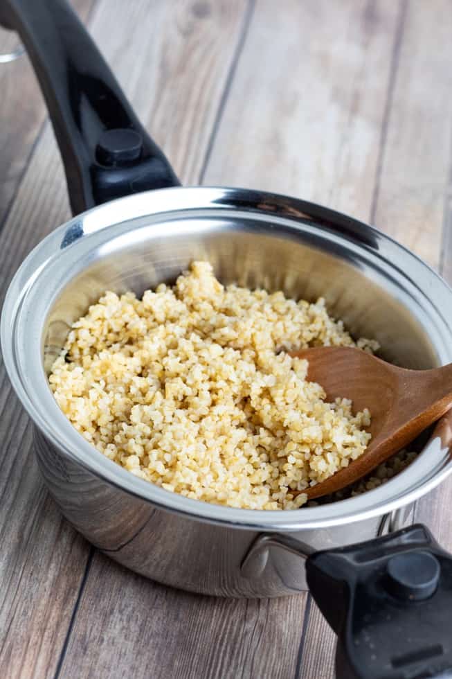 cooked bulgur in stainless pot with spoon