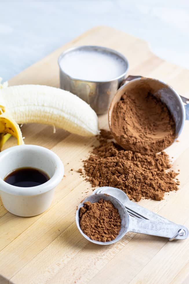 cocoa powder, almond milk, banana, vanilla on light background
