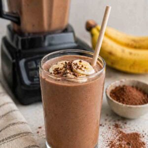 unsweetened chocolate banana smoothie in a tall glass with straw.