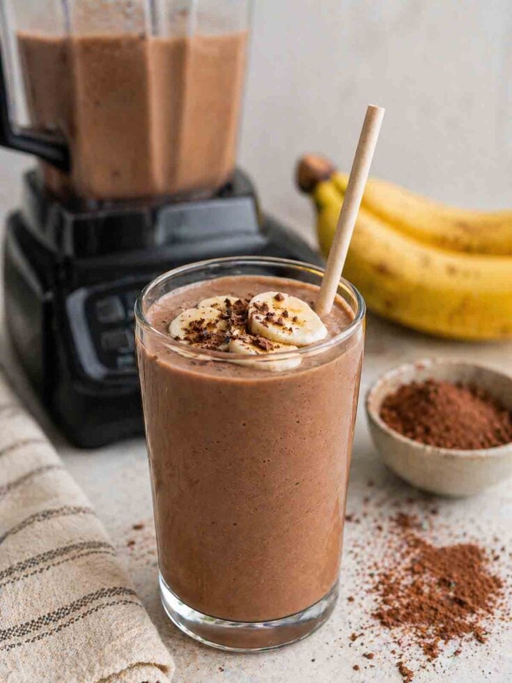 unsweetened chocolate banana smoothie in a tall glass with straw.