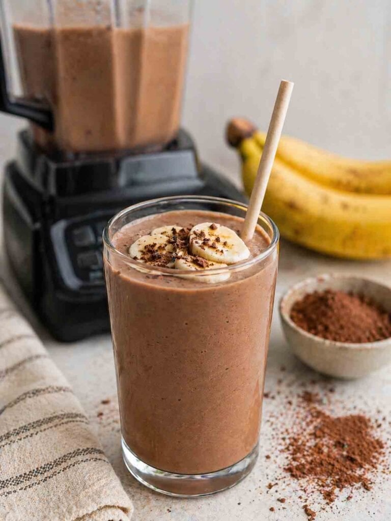 unsweetened chocolate banana smoothie in a tall glass with straw.