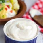 vegan sour cream in bright blue bowl with loaded baked potato in background