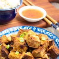 air frier tofu on blue asian bowl with chopsticks and dipping sauce in background