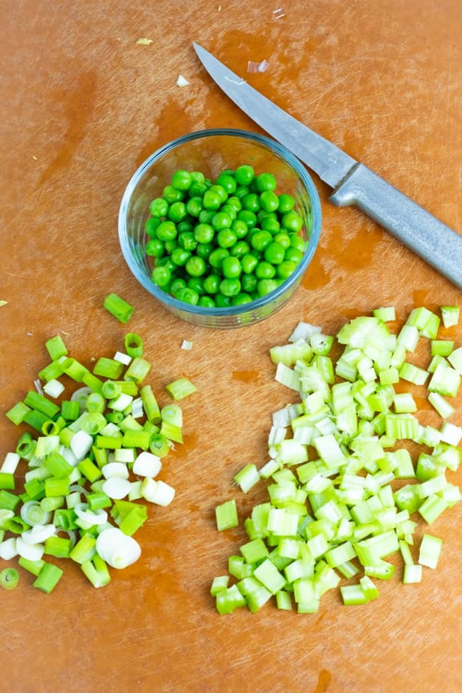 diced green onions, celery, green peas on cutting board