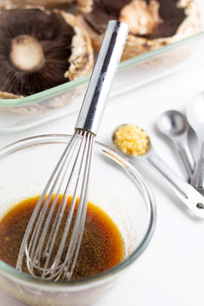 marinade sauce in glass bowl with whisk and mushrooms in background
