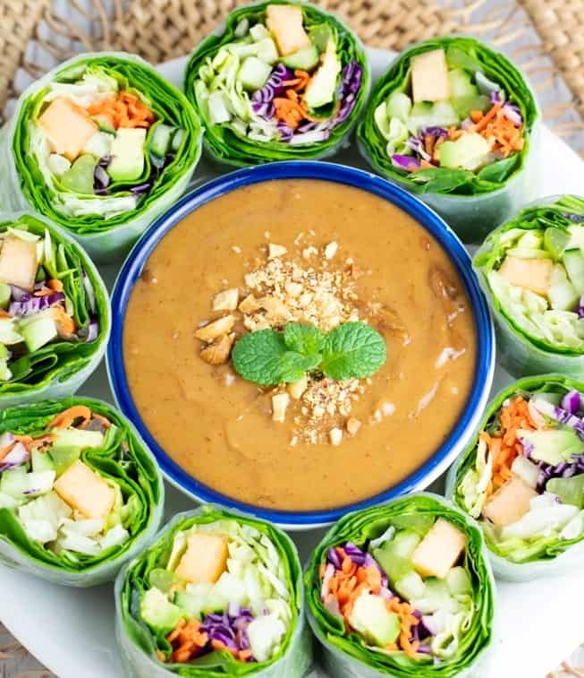 overhead of peanut sauce on platter surrounded by spring rolls