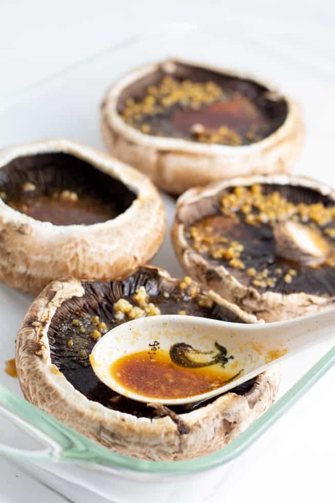 portobello mushroom caps being drizzled with marinating sauce