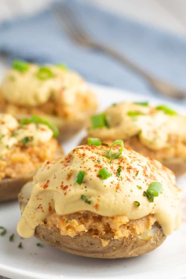 vegan baked potatoes loaded with vegan cheese and spices topped with green chives