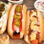 overhead shot of carrot dogs topped with chili, vegan cheese, jalepenos