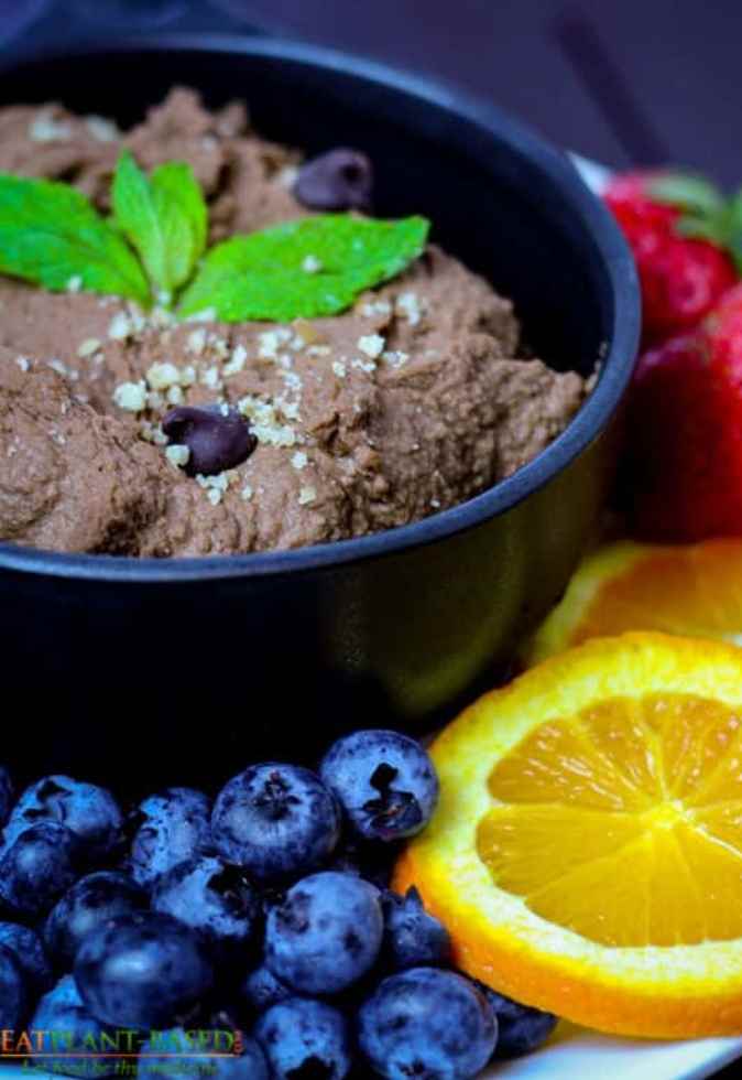 chocolate hummus in black bowl topped with mint leaves