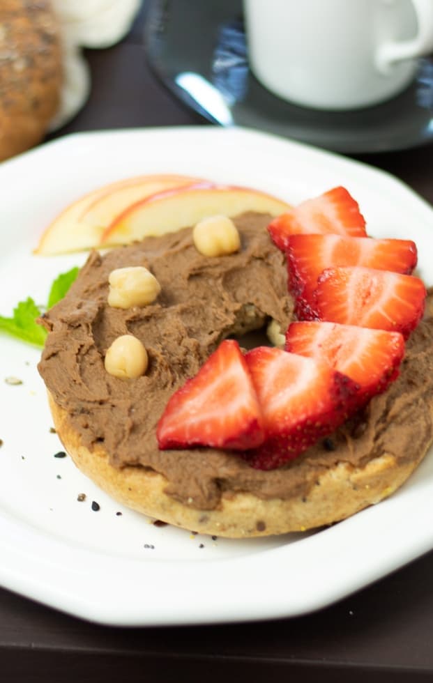 bagel topped with chocolate hummus and sliced strawberries