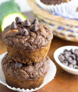chocolate zucchini vegan muffins two stacked with chocolate chips in background