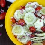 cucumber tomato salad with dill in a bright yellow bowl