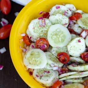 cucumber tomato salad with dill in a bright yellow bowl