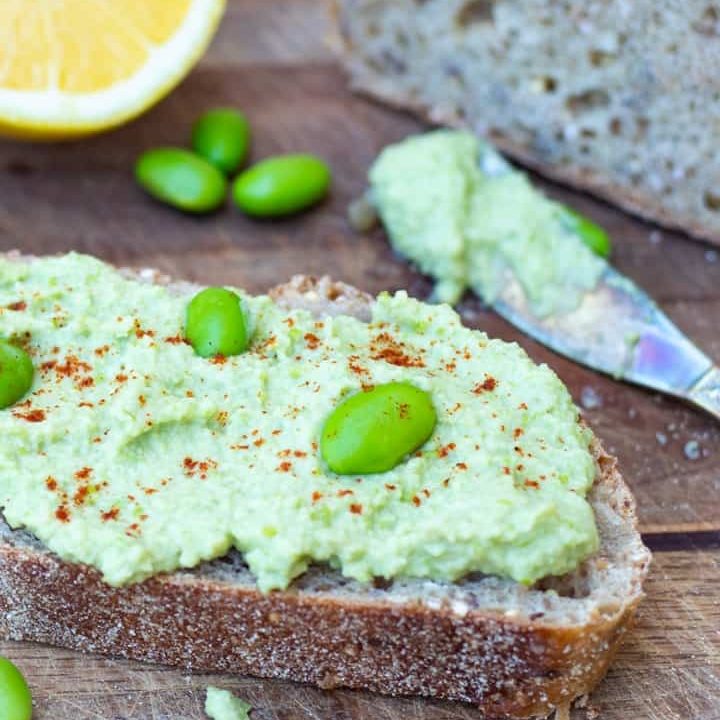 edamame hummus spread on crusty bread with spreading knive in background