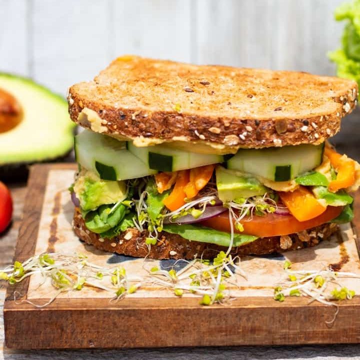 hummus sandwich with veggies on wood block