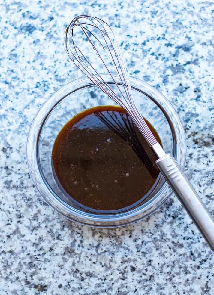 marinade in glass bowl on countertop with whisk