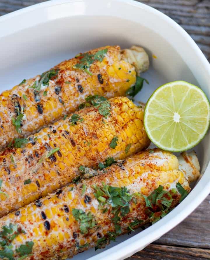 mexican corn on the cob in white dish with lime