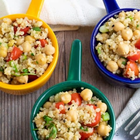 overhead shot of quinoa chickpea salad in 3 colorful bowls