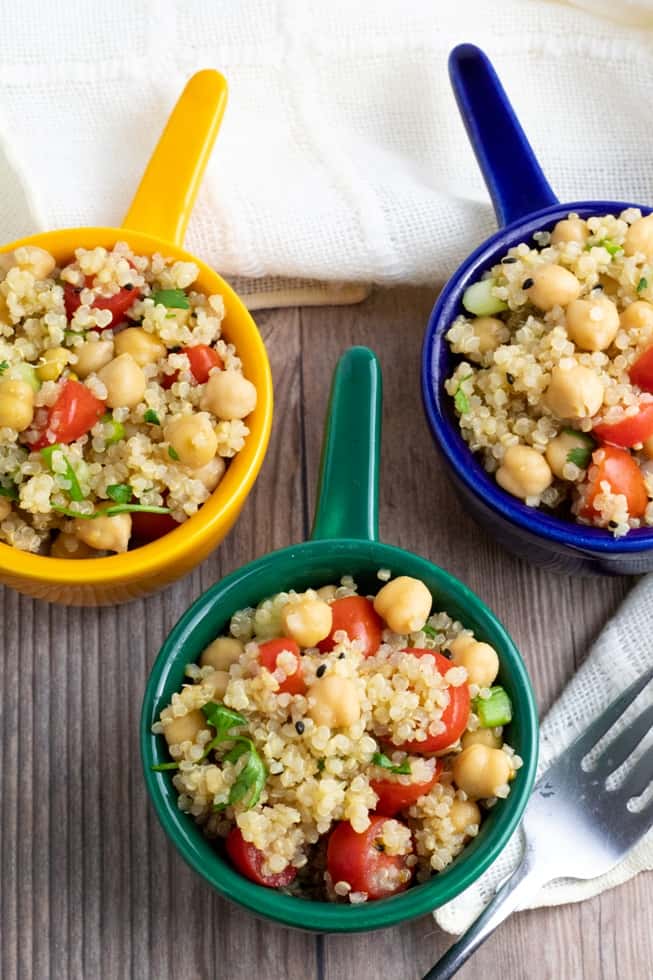 overhead shot of quinoa chickpea salad in 3 colorful bowls