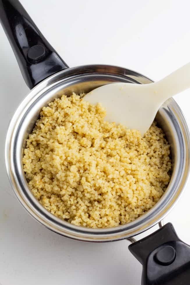 cooked quinoa in pan with white spoon