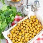 overhead photo of basket full of chickpea snack on red checkered napkin and cilantro