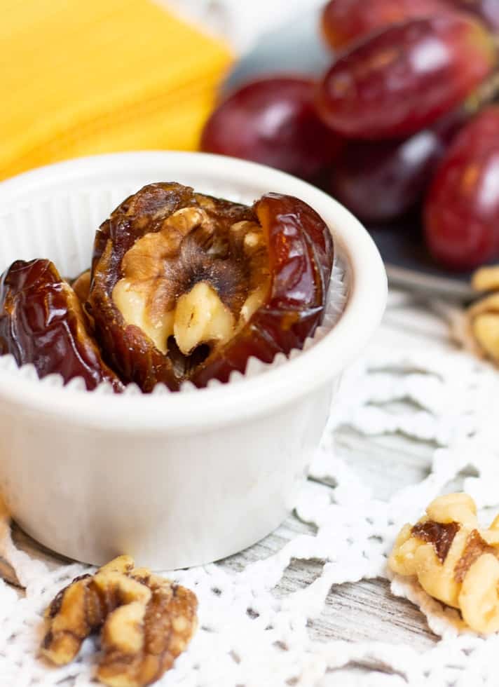 dates stuffed with walnuts in white bowl on lace tabletop