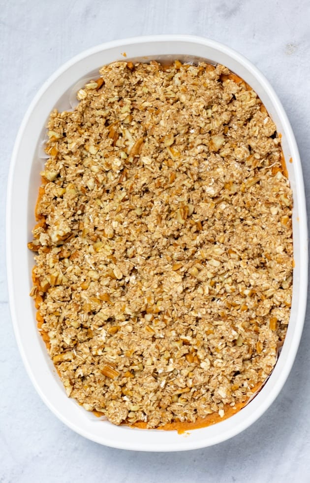 sweet potato casserole with crumble topping in white casserole dish uncooked