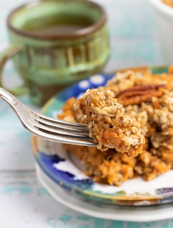 sweet potato casserole bite on fork with coffee cup on background