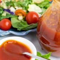 white bowl and spoon with tomato salad dressing beside salad