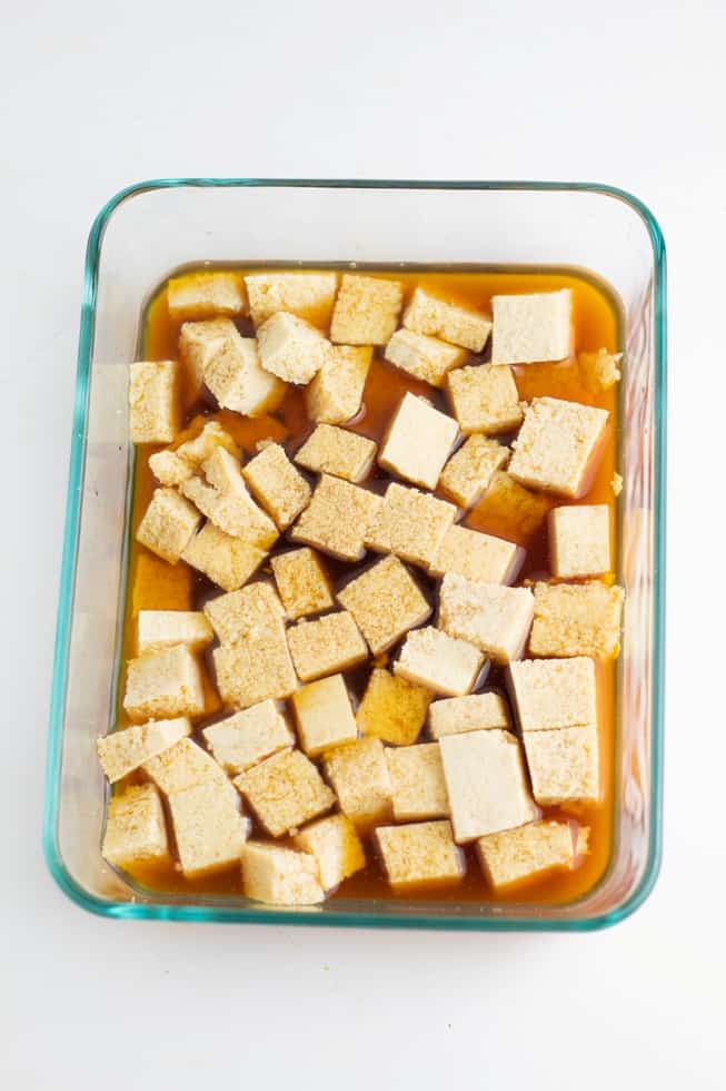 tofu cubes marinating in glass pan