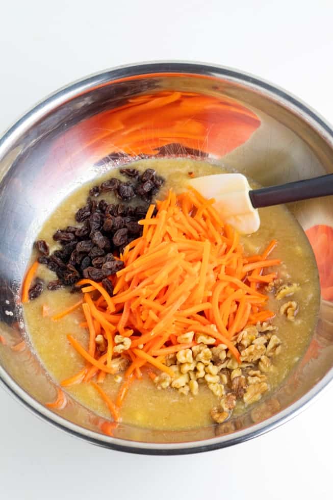 stainless bowl with carrot cake wet batter, raisins, carrots, and walnuts
