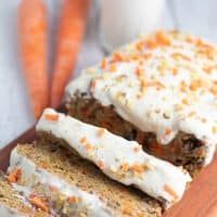 vegan carrot cake loaf with 3 pieces sliced carrots and milk in background
