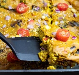 Vegan Quiche being lifted with black spatula from cast iron black pan