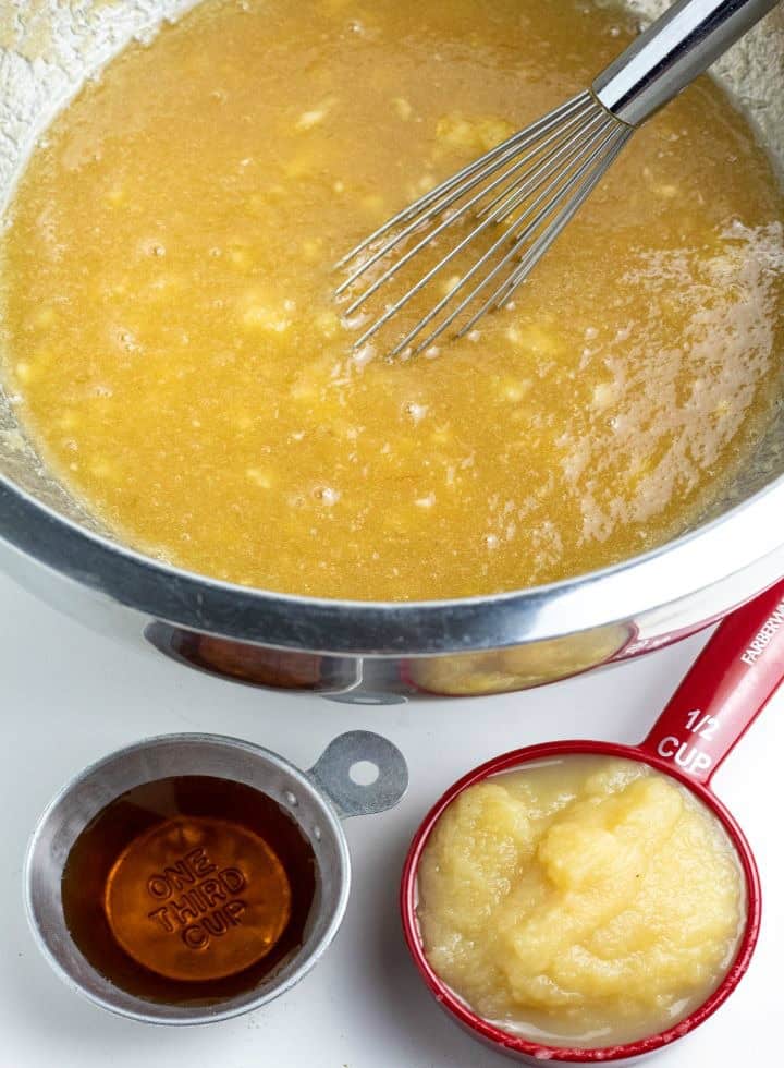 applesauce, maple syrup, and other banana bread wet ingredients in stainless bowl with whisk
