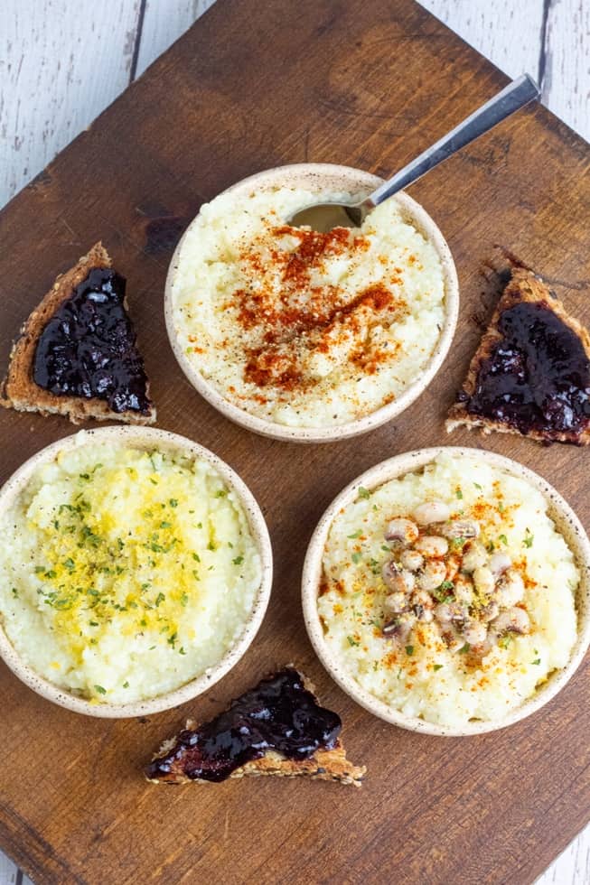 overhead shot of 3 bowls of grits seasoned with different spices and toast with grape preserves