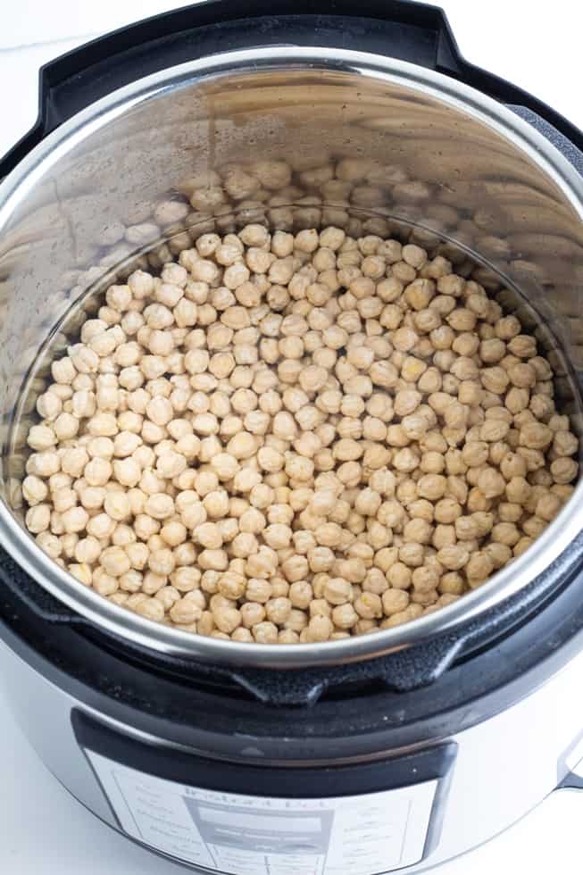 overhead photo of raw chickpeas covered with water in instantpot