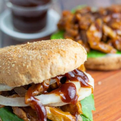 vegan barbeque sandwich on cutting board with bbq sauce in background