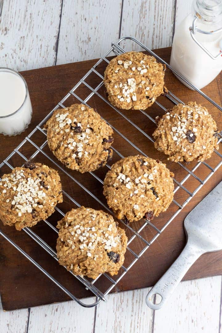 6 oatmeal vegan cookies on cooking rack with glass of almond milk