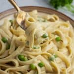 close up of vegan fettuccine alfredo on gold spoon with wooden handle