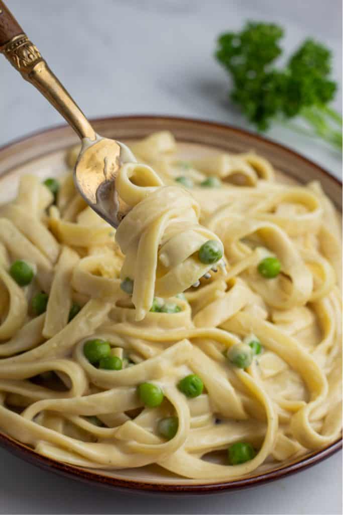 close up of vegan fettuccine alfredo on gold spoon with wooden handle