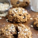 oatmeal cookie torn in half on wooden board with more cookies in background