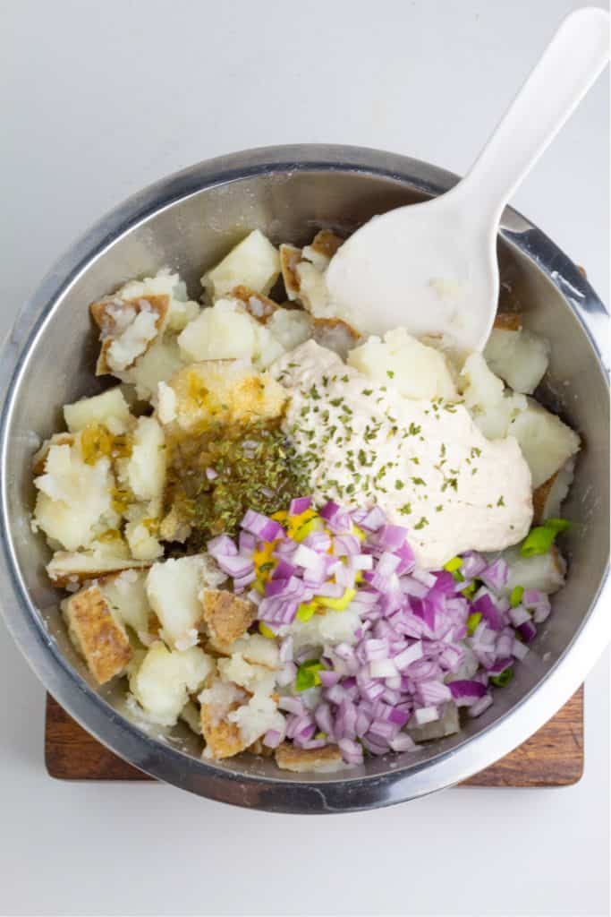 mixing bowl with cooked potatoes diced, red onion, mayo, and spices