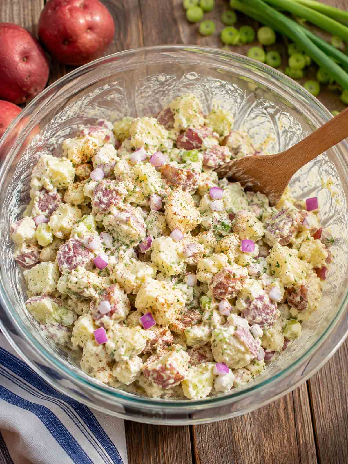 potato salad in a mixing bowl being stirred.