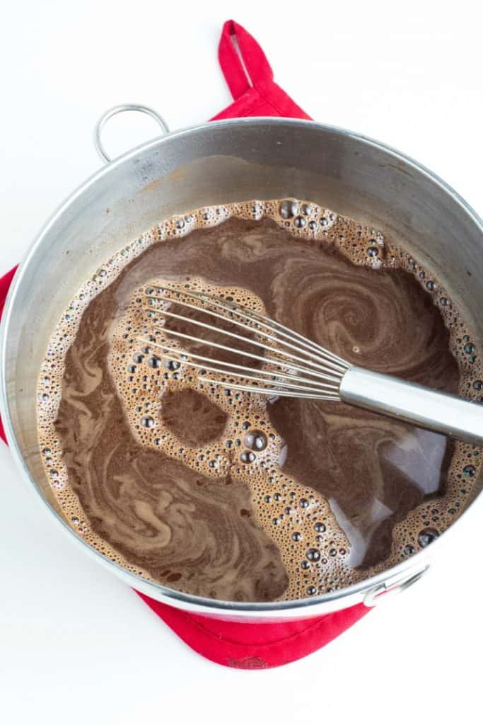 Chocolate cake frosting mix in stainless mixing bowl with whisk