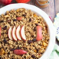 round baking glass pan with healthy apple crumble apples and cinnamon jar in background