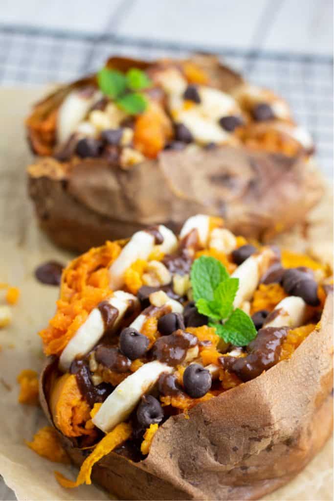baked sweet potato loaded with banana slices, chocolate, and walnuts and mint leaf