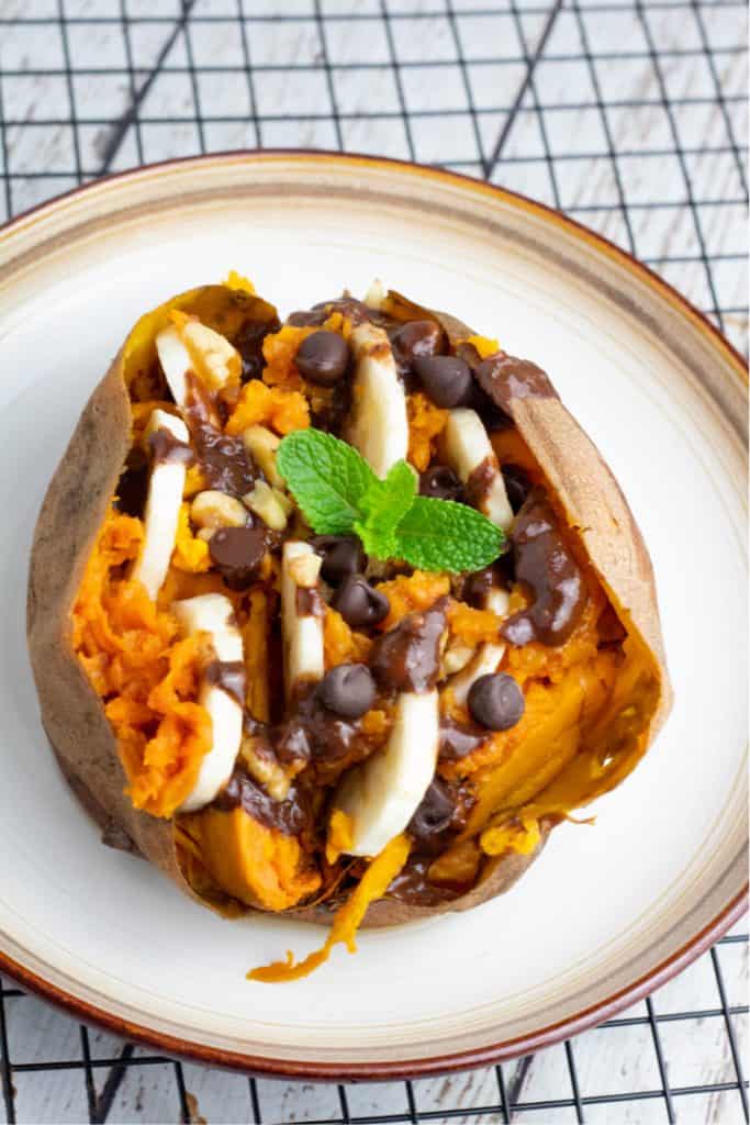 loaded sweet potato with banana slices and chocolate chips on white plate